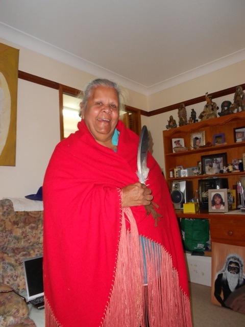 Aunty Lila with feather; a painting of Rex is visible on the bottom right side. 