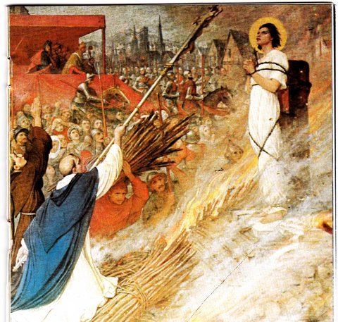 A Jailer holds up the cross for Joan to see as she is burnt
